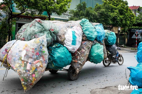 Mưu sinh ở 'thủ phủ' phế liệu ngoại thành Hà Nội- Ảnh 12. Đi dọc quốc lộ 21B, không khó để bắt gặp những chiếc xe máy thô sơ kéo theo những bao tải nhựa thải khổng lồ, gây mất an toàn giao thông - Ảnh: HOA NGUYỄN
