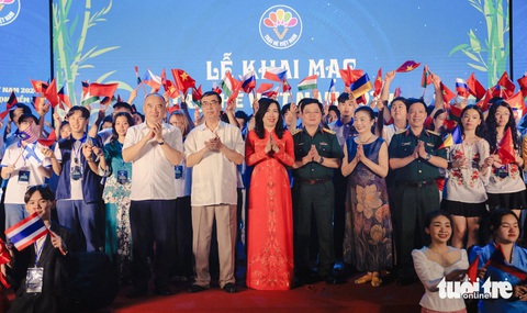 Trại hè Việt Nam: Kiều bào trẻ mong hiểu thêm văn hóa, nói tiếng Việt giỏi hơn- Ảnh 1. Thứ trưởng Bộ Ngoại giao Lê Thị Thu Hằng, chủ nhiệm Ủy ban Nhà nước về người Việt Nam ở nước ngoài (giữa) và các đại biểu chụp ảnh lưu niệm cùng kiều bào thanh niên tại lễ khai mạc Trại hè Việt Nam năm 2024, tổ chức vào tối 16-7 tại Bảo tàng Lịch sử quân sự, Hà Nội - Ảnh: DANH KHANG