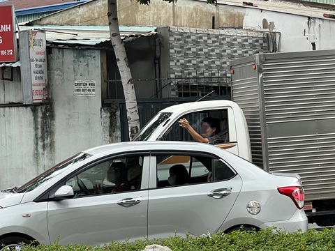 Vừa lái xe vừa phì phèo thuốc lá, mặc kệ người xung quanh lãnh 'đạn'- Ảnh 7. Tài xế vừa nhả khói, vừa đưa tay ra ngoài để gạt tàn thuốc - Ảnh: XUÂN ĐOÀN