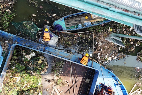 Nên phạt nặng hành vi lên cầu quăng rác xuống sông- Ảnh 1. Công nhân vệ sinh vớt rác, lục bình trên rạch Bến Nghé, TP.HCM - Ảnh: T.T.D