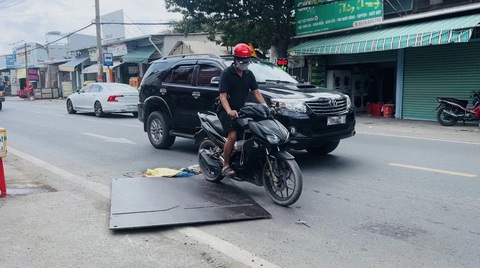 Tấm thép chỏng chơ trên đường, dân sợ té ngã lọt gầm container- Ảnh 1. Người đi đường phải nhớm người lên để giữ thăng bằng khi đi qua tấm thép chỏng chơ - Ảnh: XUÂN ĐOÀN