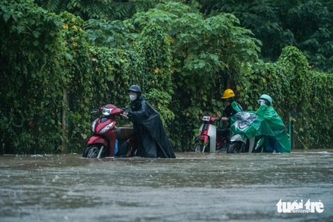 Mưa từ sáng tới đêm, người Hà Nội bì bõm dắt xe về nhà sau giờ tan ca- Ảnh 5. Ba người định dắt xe qua chỗ ngập, nhưng vì ngập quá sâu nên phải quay đầu lại - Ảnh: PHẠM TUẤN