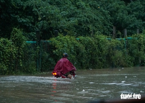 Mưa từ sáng tới đêm, người Hà Nội bì bõm dắt xe về nhà sau giờ tan ca- Ảnh 6. Một chiếc xe máy cố đi qua đoạn đường ngập sâu - Ảnh: PHẠM TUẤN