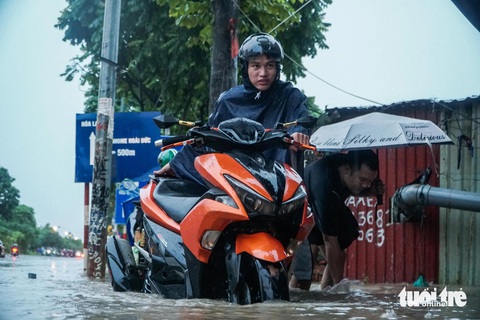 Mưa từ sáng tới đêm, người Hà Nội bì bõm dắt xe về nhà sau giờ tan ca- Ảnh 7. Nam thanh niên cố đi qua đoạn đường ngập sâu khiến xe bị chết máy - Ảnh: PHẠM TUẤN
