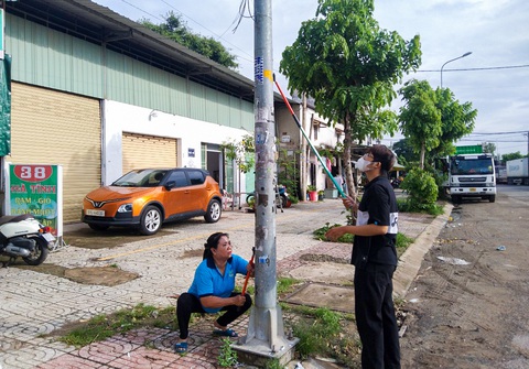 Cán bộ phường tại TP.HCM đến từng nhà dân kêu gọi bóc quảng cáo dán bậy- Ảnh 7. Một số decal dán bậy ở trên cao nên người dân phải dùng cây, đồ chuyên dụng để bóc tẩy - Ảnh: GIAI THỤY