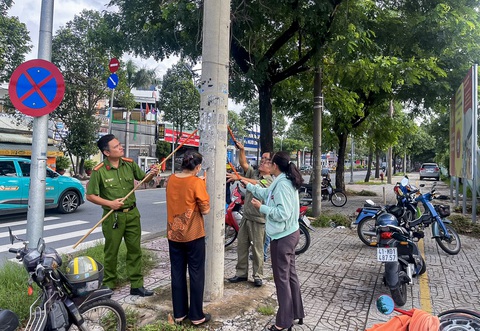 Cán bộ phường tại TP.HCM đến từng nhà dân kêu gọi bóc quảng cáo dán bậy- Ảnh 5. Người dân, công an phường, công an khu vực chung tay bóc quảng cáo dán bậy - Ảnh: GIAI THỤY