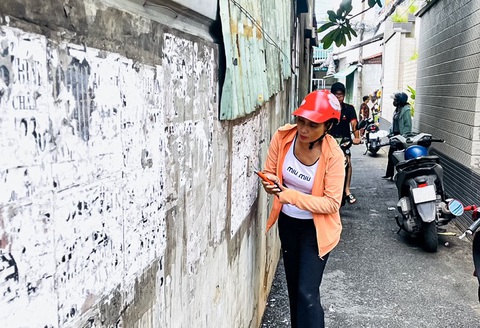Cán bộ phường tại TP.HCM đến từng nhà dân kêu gọi bóc quảng cáo dán bậy- Ảnh 3. Người dân bóc quảng cáo từ việc dán bậy tại các bức tường của những con hẻm - Ảnh: GIAI THỤY