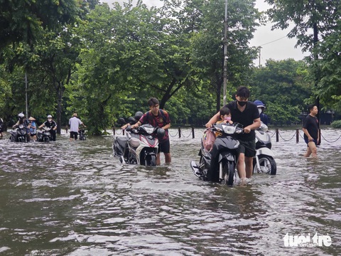 Đường Hà Nội ngập sâu từ sáng, nhiều người phải xin nghỉ làm- Ảnh 9. Khu vực hồ Văn Quán (Hà Đông, Hà Nội) nước dưới lòng hồ tràn mặt đường, ngập sâu khiến nhiều phương tiện giao thông khó khăn - Ảnh: DƯƠNG LIỄU