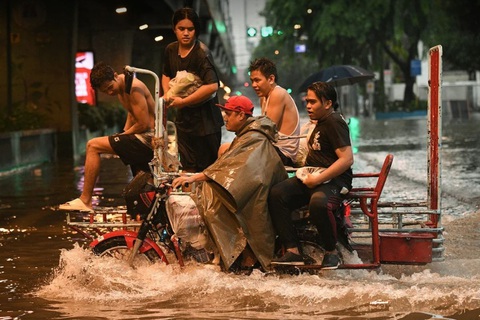 Xe ba gác chở nhiều người băng qua một con phố bị ngập ở Manila do bão Gaemi - Ảnh: GETTY IMAGES Đài Loan căng mình chờ siêu bão Gaemi, Trung Quốc cảnh báo mức cao nhất- Ảnh 2.