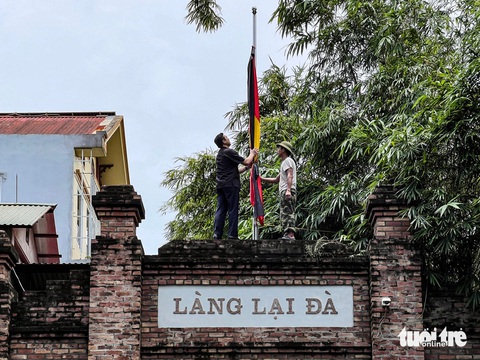 Cờ rủ được treo trên cổng thôn Lại Đà từ sáng 24-7 - Ảnh: HỒNG QUANG Lễ Quốc tang Tổng Bí thư Nguyễn Phú Trọng- Ảnh 3.