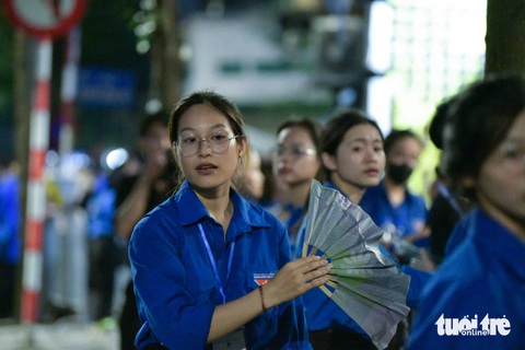 Mỗi người một chiếc quạt giấy, các bạn tình nguyện viên không ngơi tay quạt cho người dân đến viếng Tổng Bí thư được mát - Ảnh: NAM TRẦN Ướt đẫm áo xanh tình nguyện phục vụ người dân vào viếng Tổng Bí thư- Ảnh 6.