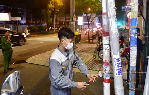 Những người dán lậu quảng cáo trái phép bị Công an phường Võ Thị Sáu, quận 3 phạt cạo sạch quảng cáo trên tuyến đưởng Nguyễn Thị Minh Khai - Ảnh: T.T.D Bao giờ hết đi bóc quảng cáo dán bậy?- Ảnh 1.