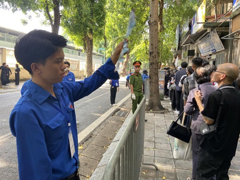 Lý Dào Quyên với cánh tay còn lại duy nhất đứng quạt mát cho dòng người vào viếng Tổng Bí thư Nguyễn Phú Trọng trên phố Tăng Bạt Hổ sáng 26-7 - Ảnh: T.ĐIỂU Người dân xếp quạt cây ra đường, pha nước chanh cho người đến viếng Tổng Bí thư Nguyễn Phú Trọng- Ảnh 12.