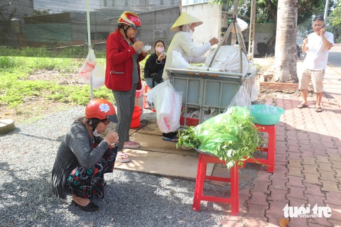 Không đủ ghế, nhiều khách hàng ngồi xổm xuống đất để thưởng thức tàu hủ của cô Năm - Ảnh: THÙY LINH Cụ bà 70 tuổi bán tàu hủ nuôi con ăn học thành tài- Ảnh 4.