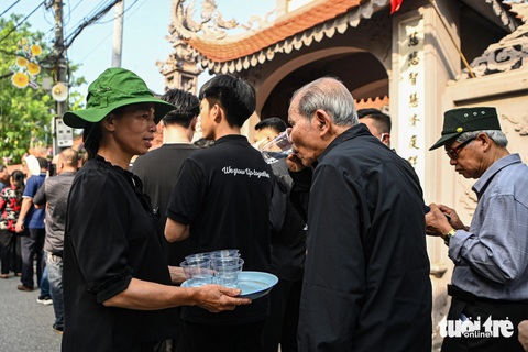 Người dân thôn Lại Đà mời người dân đến viếng Tổng Bí thư nước mát khi trời nắng to - Ảnh: HỒNG QUANG Người dân xếp quạt cây ra đường, pha nước chanh cho người đến viếng Tổng Bí thư Nguyễn Phú Trọng- Ảnh 1.