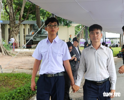 Tổng Bí thư Nguyễn Phú Trọng là ánh sáng cho thế hệ trẻ soi mình phấn đấu- Ảnh 1. Ông Nguyễn Mạnh Hùng (quận Phú Nhuận) dắt tay cậu con trai đến viếng Tổng Bí thư Nguyễn Phú Trọng sáng 26-7 - Ảnh: CẨM NƯƠNG