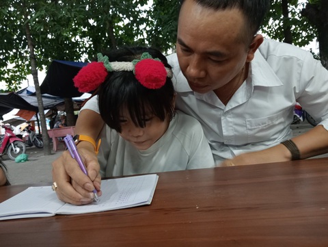 Lớp học tình thương dưới mái hiên ngôi miếu cũ- Ảnh 1. Anh Đỗ Thiện Thành rèn từng nét chữ cho em nhỏ - Ảnh: ĐỊNH DƯƠNG