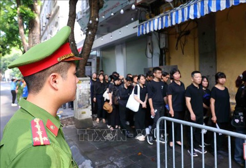 Lực lượng vũ trang bảo đảm an ninh, an toàn Lễ Quốc tang Tổng Bí thư Nguyễn Phú Trọng- Ảnh 10. Cán bộ, chiến sĩ Công an thành phố Hà Nội làm nhiệm vụ trên phố Nguyễn Công Trứ, giúp người dân vào Nhà tang lễ Quốc gia sáng 26-7