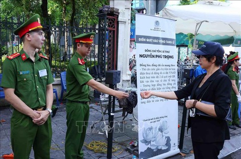 Lực lượng vũ trang bảo đảm an ninh, an toàn Lễ Quốc tang Tổng Bí thư Nguyễn Phú Trọng- Ảnh 1. Lực lượng công an giúp người dân quét mã QR để vào Nhà tang lễ Quốc gia, số 5 Trần Thánh Tông, Hà Nội, sáng 26-7