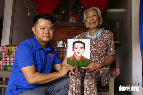 Chàng bí thư xã đoàn tìm lại dáng hình các anh hùng liệt sĩ- Ảnh 1. Anh Hồ Xuân Hoàng (bí thư Đoàn xã Quảng Thái, huyện Quảng Điền, Thừa Thiên Huế) tặng lại di ảnh liệt sĩ Phan Thịnh đã được anh phục hồi cho mẹ Việt Nam anh hùng Văn Thị Giao - Ảnh: NHẬT LINH
