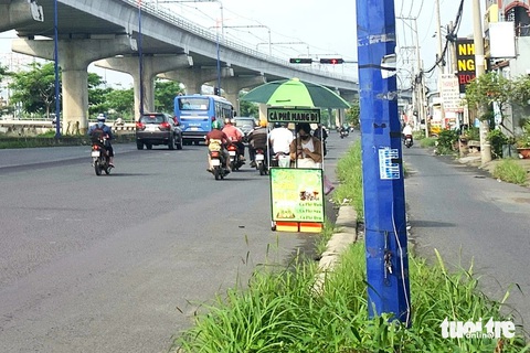 Đèn chiếu sáng song hành xa lộ Hà Nội không hoạt động, người dân vừa đi đường vừa run- Ảnh 3. Một cột đèn bị kẻ xấu cạy phá nắp trộm thiết bị bên trong, đơn vị quản lý phải dùng băng keo để đấu nối lại - Ảnh: TIẾN QUỐC