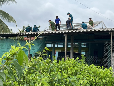 Mưa lớn làm sập, tốc mái 78 căn nhà tại Tiền Giang- Ảnh 4. Lực lượng công an, dân quân và các bạn đoàn viên thanh niên đang giúp người dân lợp lại các mái nhà bị tốc máy do lốc xoáy gây ra - Ảnh: H.T.