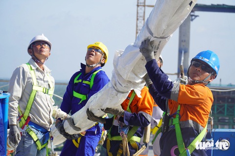 Cầu Rạch Miễu 2 căng cáp dây văng đầu tiên- Ảnh 1. Các công nhân, kỹ sư đang tiến hành căng dây văng đầu tiên của cầu Rạch Miễu 2 - Ảnh: MẬU TRƯỜNG