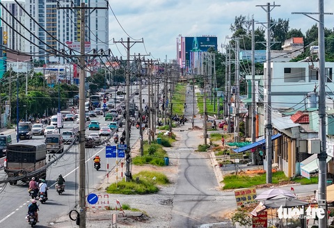 Quốc lộ 13 Bình Dương đã mở rộng nhưng vẫn nằm chờ di dời lưới điện- Ảnh 1. Trụ điện cũ mới chằng chịt dọc quốc lộ 13 (đoạn qua tỉnh Bình Dương) - Ảnh: CHÂU TUẤN