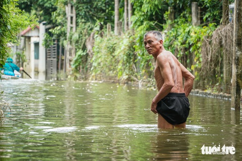 Về rốn lũ Chương Mỹ chứng kiến người Hà Nội ở nhà phao, đi thuyền trên phố- Ảnh 22. Một người đàn ông phải lội nước để đi về nhà - Ảnh: PHẠM TUẤN