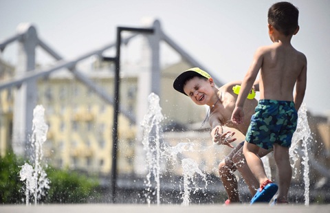 Thủ đô nước Nga nắng nóng nhất trăm năm qua- Ảnh 1. Trẻ em chơi đùa dưới đài phun nước trong nắng nóng ở trung tâm Mátxcơva vào ngày 3-7-2024 - Ảnh: AFP