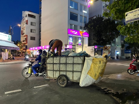 Đề xuất cấm xe rác thô sơ, xe nào vô hẻm gom rác?- Ảnh 4. Xe vừa chạy trên đường, người phụ nữ vừa đứng trên thùng xe để ấn rác xuống dưới