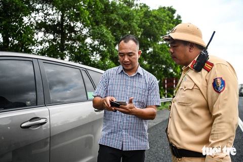 Cận cảnh quy trình tạm giữ giấy tờ của tài xế vi phạm trên VNeID- Ảnh 13. Ngoài ra, nhiều tài xế hiện chưa tích hợp giấy tờ trên VNeID cũng được cảnh sát khuyến khích, nhắc nhở đồng thời hướng dẫn họ thực hiện - Ảnh: HỒNG QUANG