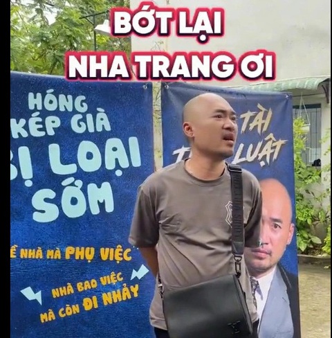 Tiến Luật đứng bên bảng cổ vũ không giống ai của vợ Thu Trang - Ảnh: Chụp từ clip Tiến Luật đứng bên tấm bảng cổ vũ không giống ai của vợ