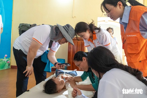 Tình nguyện viên Hàn Quốc 'chữa lành' trẻ em khuyết tật Quảng Trị- Ảnh 2. Chị Nguyễn Thị Thu Trang (áo xanh) được các tình nguyện viên hướng dẫn cách chăm sóc răng miệng cho con - Ảnh: HOÀNG TÁO