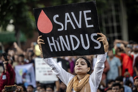 Một phụ nữ giơ bảng kêu gọi bảo vệ nhóm người thiểu số theo đạo Hindu của Bangladesh ở Dhaka ngày 9-8 - Ảnh: AFP Cảnh sát bãi công, cả ngàn tù nhân Bangladesh vượt ngục- Ảnh 2.