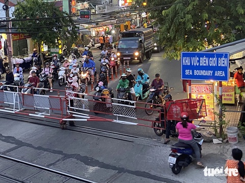 Dừng xe chờ tàu hỏa tràn sang cả làn ngược chiều, có nhanh hơn không?- Ảnh 2. Không chỉ dừng tàu dàn ra hết bên ngoài rào chắn, có người còn cố luồn vào bên trong - Ảnh: LỆ XUÂN