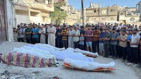 Israel không kích trường học ở Dải Gaza khiến 93 người chết, bị cáo buộc 'diệt chủng'- Ảnh 2. Người Palestine cầu nguyện bên cạnh thi thể của những người Palestine thiệt mạng trong cuộc không kích của Israel vào trường học tại thành phố Gaza, Dải Gaza ngày 10-8 - Ảnh: REUTERS