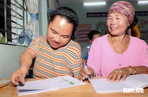 Người mẹ gần 60 tuổi đẩy xe lăn cùng con đến lớp xóa mù chữ- Ảnh 2. Dù mới học được gần 3 tháng, nhưng hai mẹ con bà Thành Thị Thiên và Lý Thị Hương đã đọc thông, viết thạo - Ảnh: DUY NGỌC