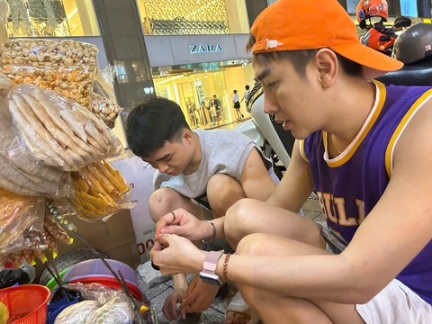Vincent và bạn đi cùng phụ bà Kim Cương lột vỏ trứng cho khách - Ảnh: NGUYỄN HOÀNG TUẤN Gánh hàng rong độc lạ 'viral' trên mạng: Bà chủ quán đêm nào cũng ngủ quên, khách tự trộn bánh tráng- Ảnh 1.