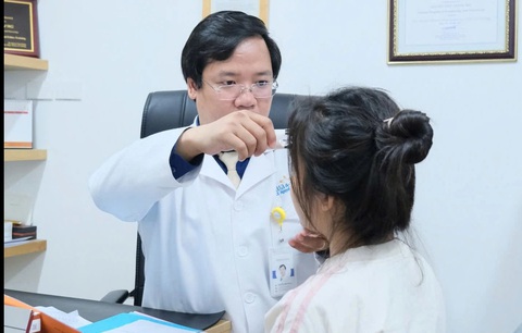 Bác sĩ Nguyễn Tiến Thành thăm khám cho bệnh nhân biến chứng do tự nặn mụn ở nhà gây bội nhiễm - Ảnh: Bác sĩ cung cấp Cô gái sưng lệch mặt vì tự nặn mụn, đắp thuốc đông y- Ảnh 1.