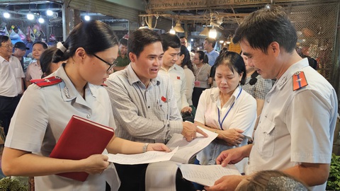 Xuyên đêm kiểm tra chợ đầu mối Thủ Đức, phát hiện nhiều lỗ hổng quản lý- Ảnh 2. Ông Cao Thanh Bình (áo dài tay) kiểm tra khâu ghi chép, quản lý nguồn gốc hàng hóa tại chợ đầu mối Thủ Đức - Ảnh: N.TRÍ