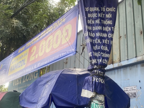 Băng rôn quảng cáo bủa vây gốc cây, cột điện, che lấp biển báo giao thông- Ảnh 8. Dây băng rôn quảng cáo cột vào tấm băng rôn tuyên truyền đã đặt trước đó trên đường Hương lộ 2, quận Bình Tân - Ảnh: HỒNG ĐIỆP