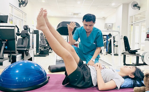 Chuyên gia vật lý trị liệu tại Viện Vật lý y sinh học hướng dẫn một bệnh nhân trong điều trị vẹo cột sống - Ảnh: MỸ DUNG Học sinh chữa vẹo cột sống với thiết bị chuyên dụng- Ảnh 1.