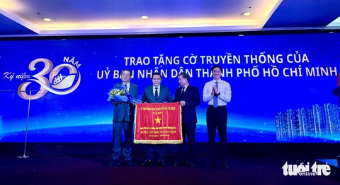 TP.HCM 'số hóa' đường thủy, kỳ vọng phát triển sông Sài Gòn như mô hình ở Paris- Ảnh 1. Lãnh đạo Sở Giao thông vận tải TP.HCM (bên phải) trao cờ truyền thống của UBND TP.HCM cho Trung tâm Quản lý đường thủy nhân kỷ niệm 30 năm thành lập - Ảnh: THU DUNG