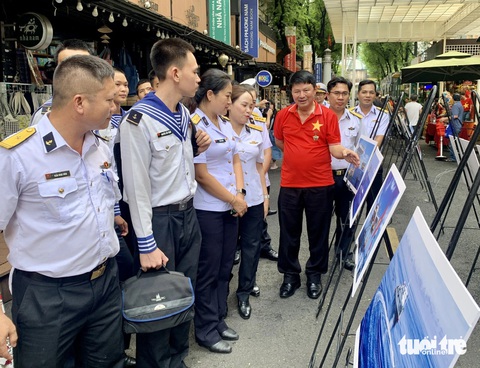 Chủ tịch Hội Nhiếp ảnh TP.HCM Đoàn Hoài Trung (áo đỏ) chia sẻ câu chuyện đằng sau những bức ảnh - Ảnh: HOÀI PHƯƠNG Cuộc sống quân và dân Trường Sa qua ảnh- Ảnh 7.