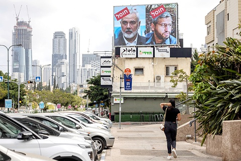 Một tấm bảng có ảnh chân dung thủ lĩnh quân sự Hamas Mohammed Deif (phải) và thủ lĩnh chính trị Hamas Ismail Haniyeh với dòng chữ “đã bị ám sát” bằng tiếng Do Thái tại Tel Aviv, Israel ngày 2-8 - Ảnh: AFP Giá dầu nhảy múa trên 'chảo lửa' Trung Đông- Ảnh 1.