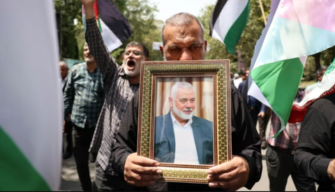 Báo Telegraph: Israel thuê điệp viên Iran đặt bom ám sát thủ lĩnh Hamas- Ảnh 1. Người dân cầm di ảnh của thủ lĩnh Hamas Ismail Haniyeh và vẫy cờ Palestine ở thủ đô Tehran ngày 31-7 - Ảnh: SHUTTERSTOCK