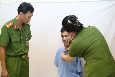 Người khuyết tật ở TP.HCM được cấp căn cước: 'Tôi vui lắm, sẽ giữ nó thật kỹ'- Ảnh 3. Cán bộ công an ân cần, cài lại nút áo cho thanh niên mất hai cánh tay trước khi chụp ảnh làm căn cước - Ảnh: MINH HÒA