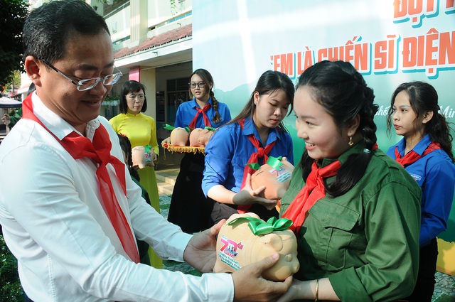 Chú Trương Quốc Lâm (bí thư Quận ủy quận 11)  trao heo đất cho các bạn đội viên. Ảnh: NGUYỄN HƯNG