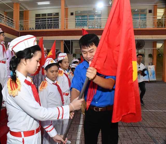 Anh Nguyễn Đình Quý - bí thư Quận Đoàn, chủ tịch Hội đồng đội, giám đốc Nhà thiếu nhi quận 5 trao cờ tổ quốc cho các chi đội . - Ảnh: N. HƯNG